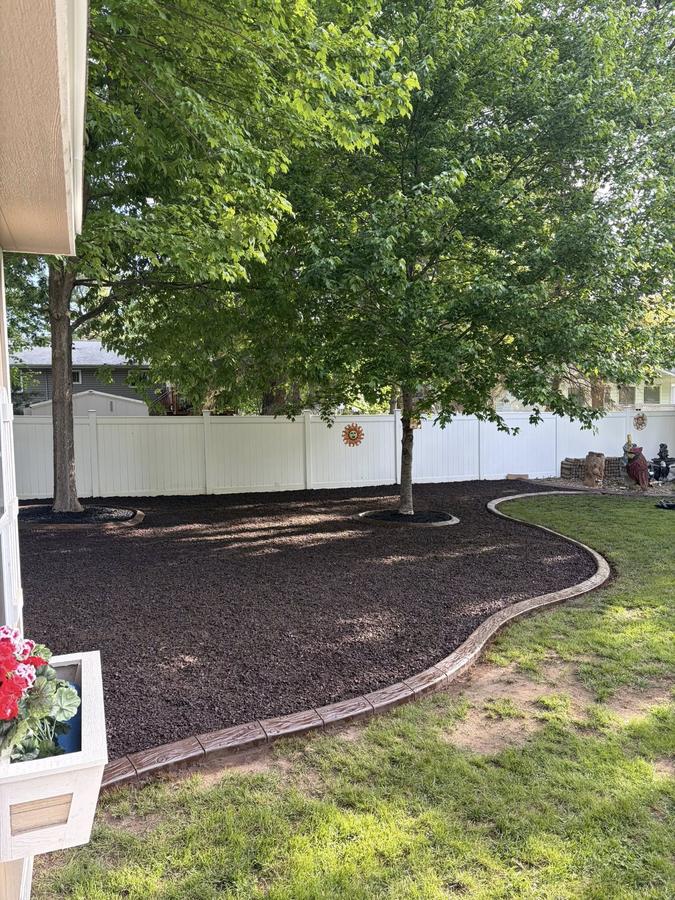 Backyard landscape bed finished with continuous concrete curb edging.