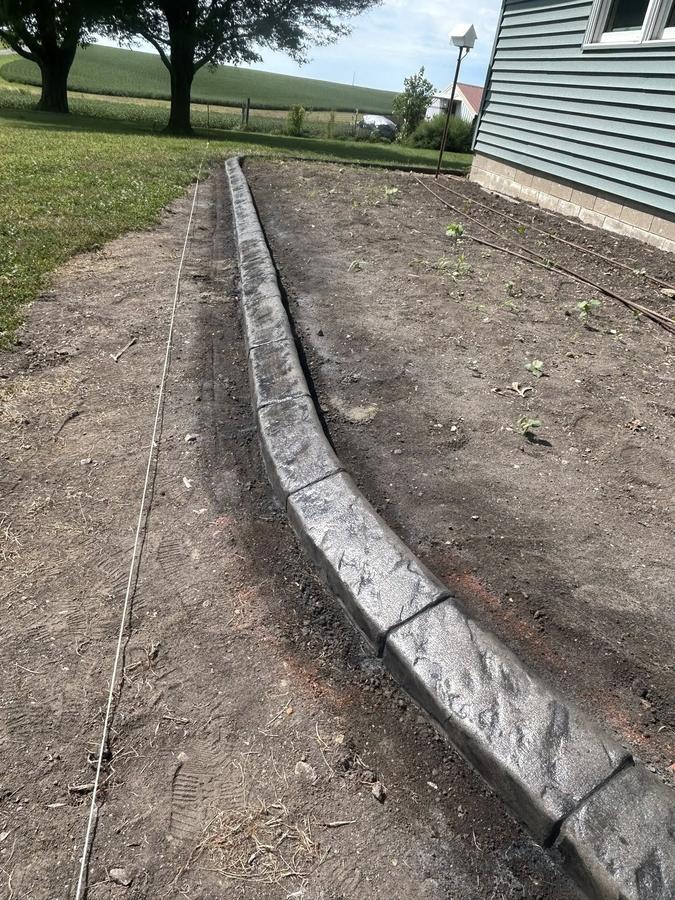 Freshly installed gray concrete landscape curbing along a home walkway.