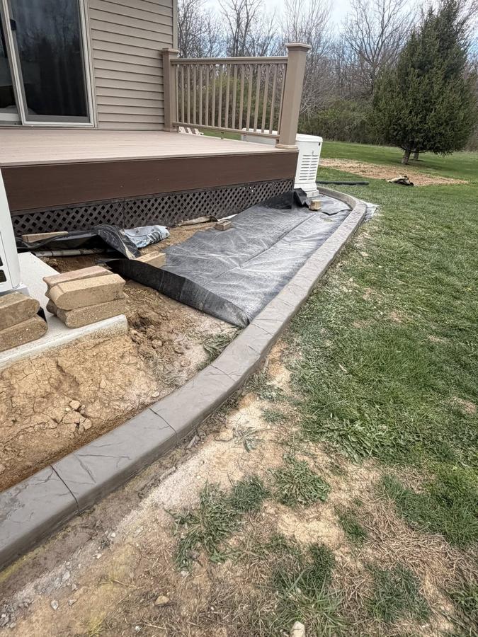 Gray decorative curbing around a patio-side landscape bed.