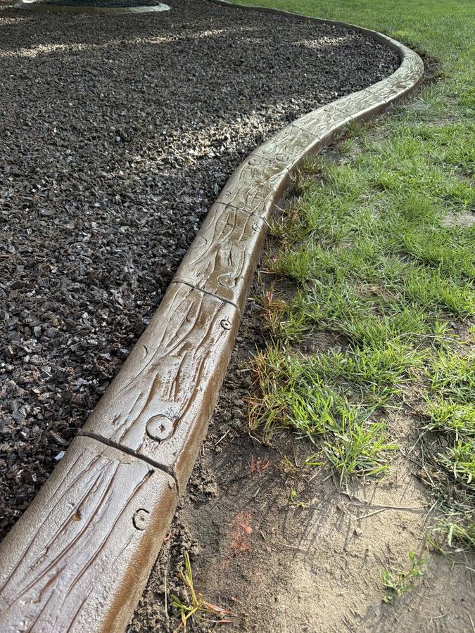 Textured gray curb line separating lawn from landscape bed.