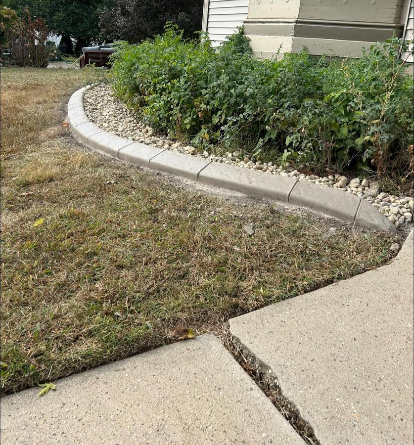 Bright concrete landscape border wrapping a front flower bed near a sidewalk.